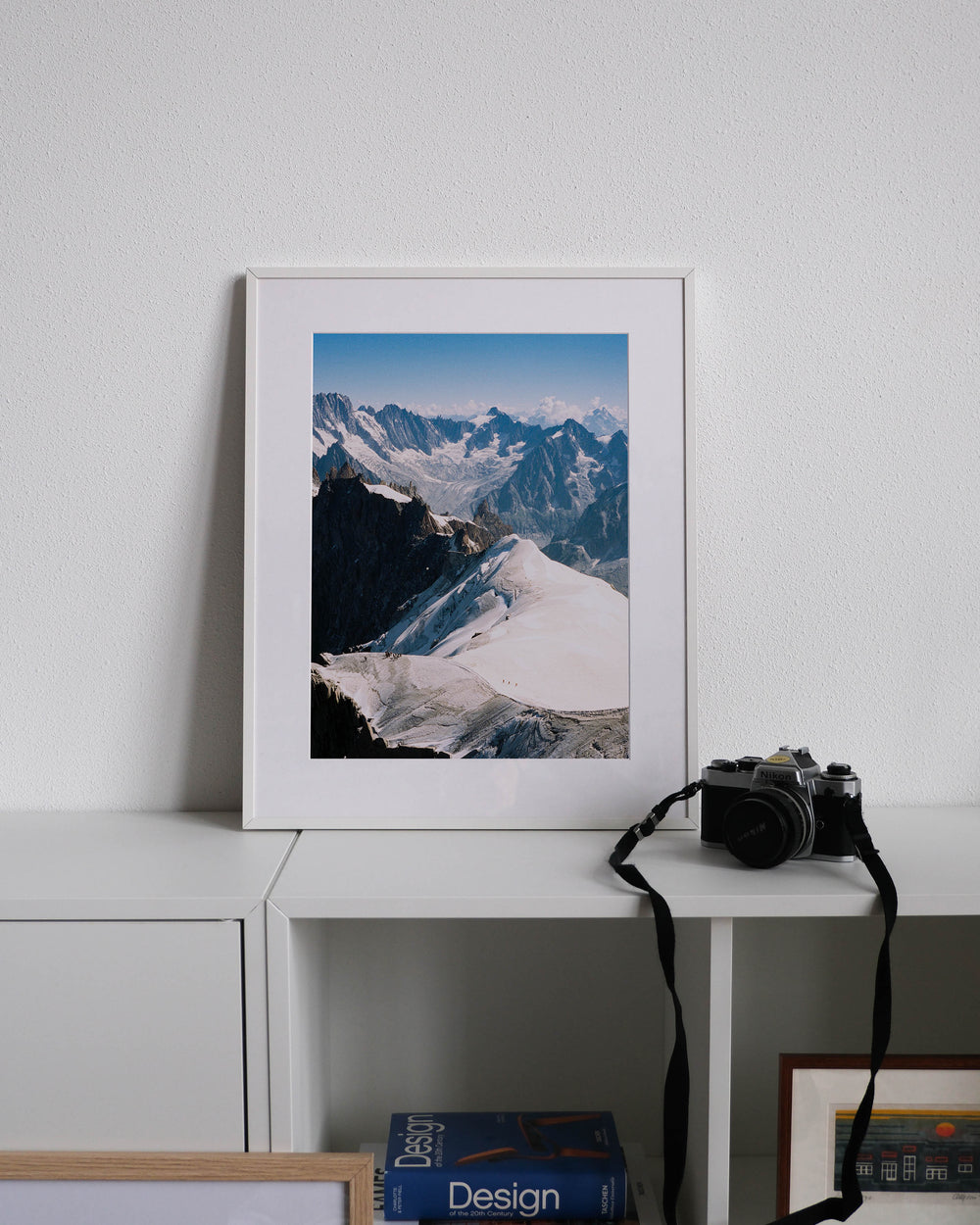 Framed analog photo print on Fujifilm paper featuring Analog photo print on Fujifilm paper featuring climbers navigating the ridges of Mont Blanc in the French Alps. Captured from the Aiguille du Midi at 3842 meters. Displayed on a modern white cabinet with a minimalist interior setting.