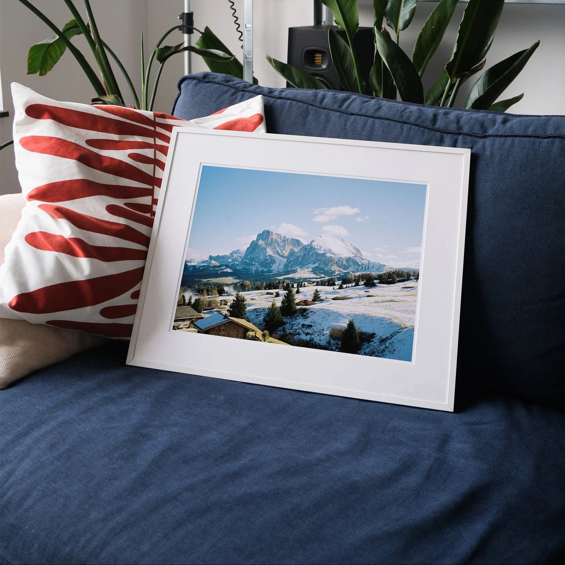 Framed analog photo print on Fujifilm paper showcasing the soft, pastel hues of the Dolomite mountains, with layered peaks and misty valleys, titled Dolomite Bliss, displayed on a neutral-toned couch in a serene, minimalist interior.