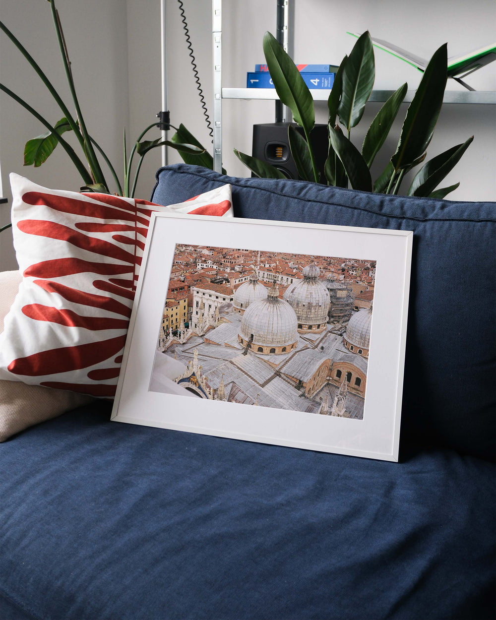 Framed analog photo print on Fujifilm paper featuring the domes of Basilica San Marco in Venice, captured from above, showcasing its intricate architecture and iconic design. Displayed on a blue couch with a minimalist interior setting.