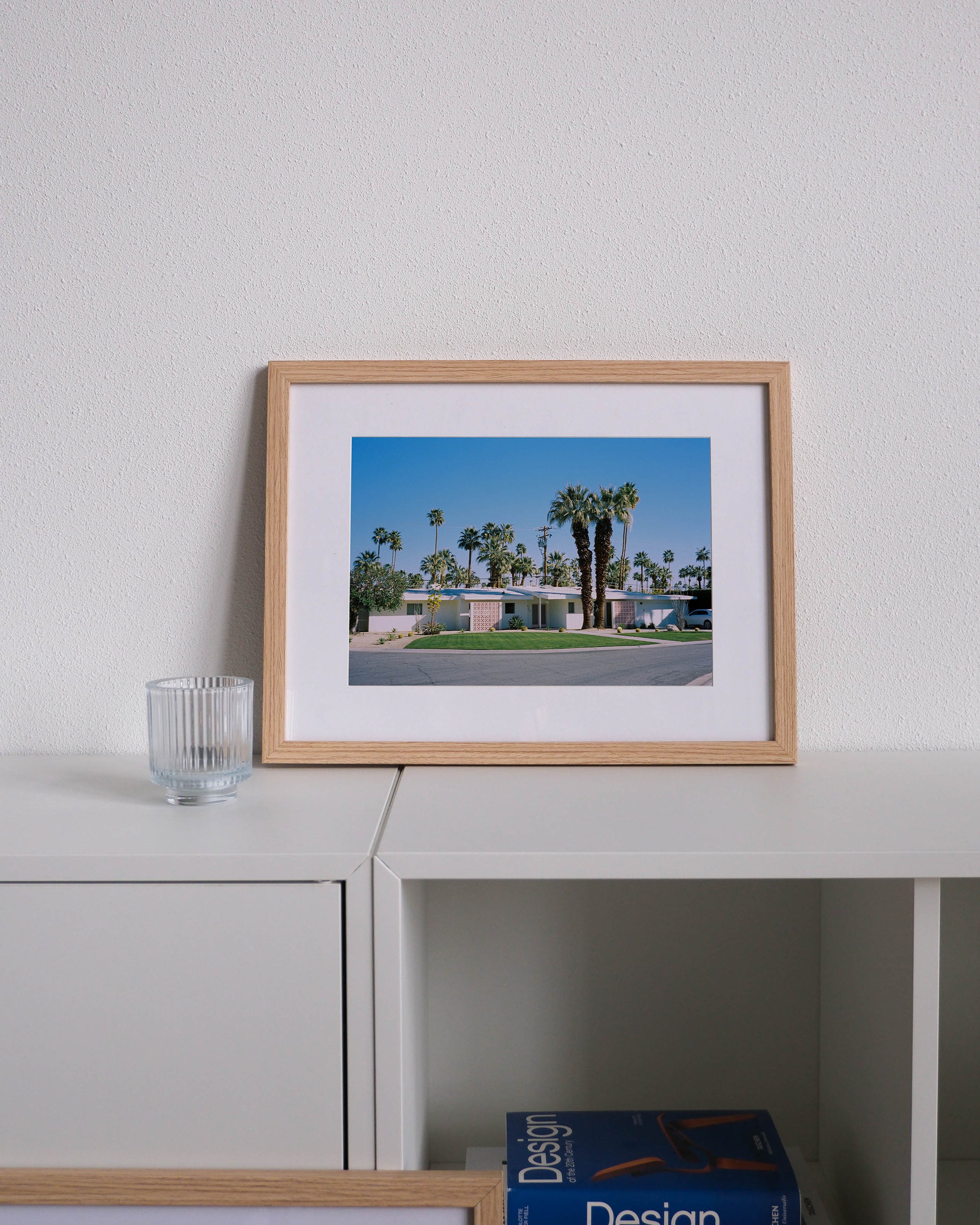 Framed analog photo print on Fujifilm paper featuring a midcentury modern home in Palm Springs, displayed on a modern white cabinet with a minimalist interior setting.