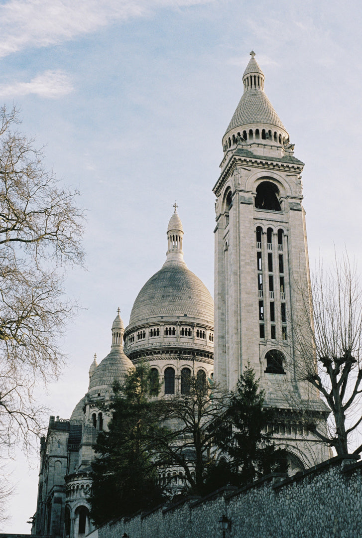 Analog photo print on Fujifilm paper featuring the towers of Sacré-Cœur in winter, bathed in sunlight with a clear blue sky above.