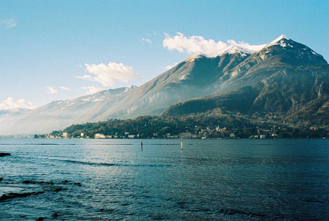 Analog photo print on Fujifilm paper featuring a mountain peak on Lake Como in winter, with mist drifting across the slopes and sunlight breaking through.