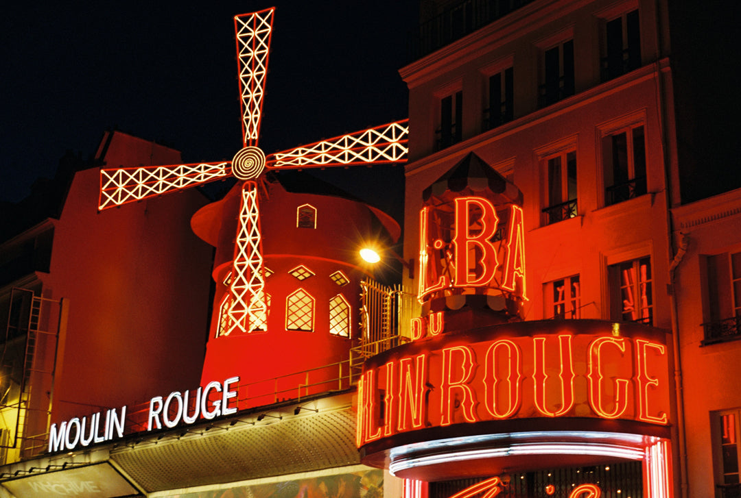 Analog photo print on film featuring the iconic Moulin Rouge at night, with its bright red lights glowing against the Parisian night sky.