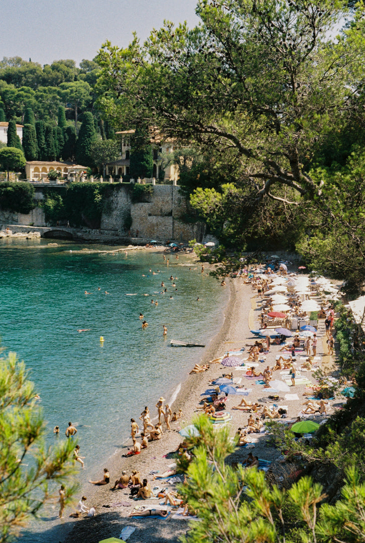 Analog photo print featuring the vibrant atmosphere of Paloma Beach in Saint-Jean-Cap-Ferrat, with sunbathers on the sands, the Mediterranean Sea, and luxurious villas along the coastline.