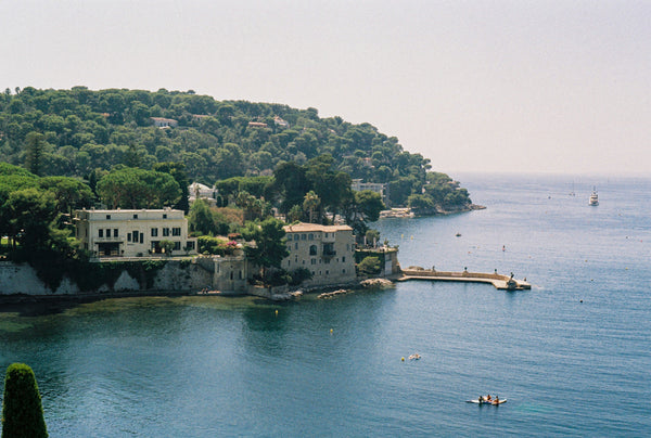 Analog photo print featuring Saint-Jean-Cap-Ferrat on the French Riviera, with lush trees, paddle boarders on the Mediterranean, and luxurious villas along the coast.