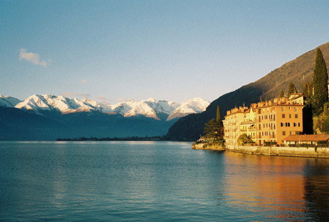 Analog photo print on Fujifilm paper featuring houses along Lake Como in Bellano during golden hour, with snow-capped peaks.