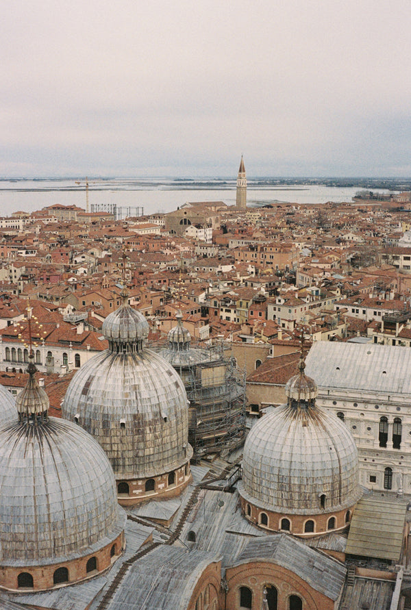 Analog photo print on Fujifilm paper featuring the Basilica di San Marco rising above Venice’s terracotta rooftops, captured from the Loggetta del Sansovino. The scene offers a raw view of the city, with scaffolding and cranes reflecting Venice’s blend of tradition and change.